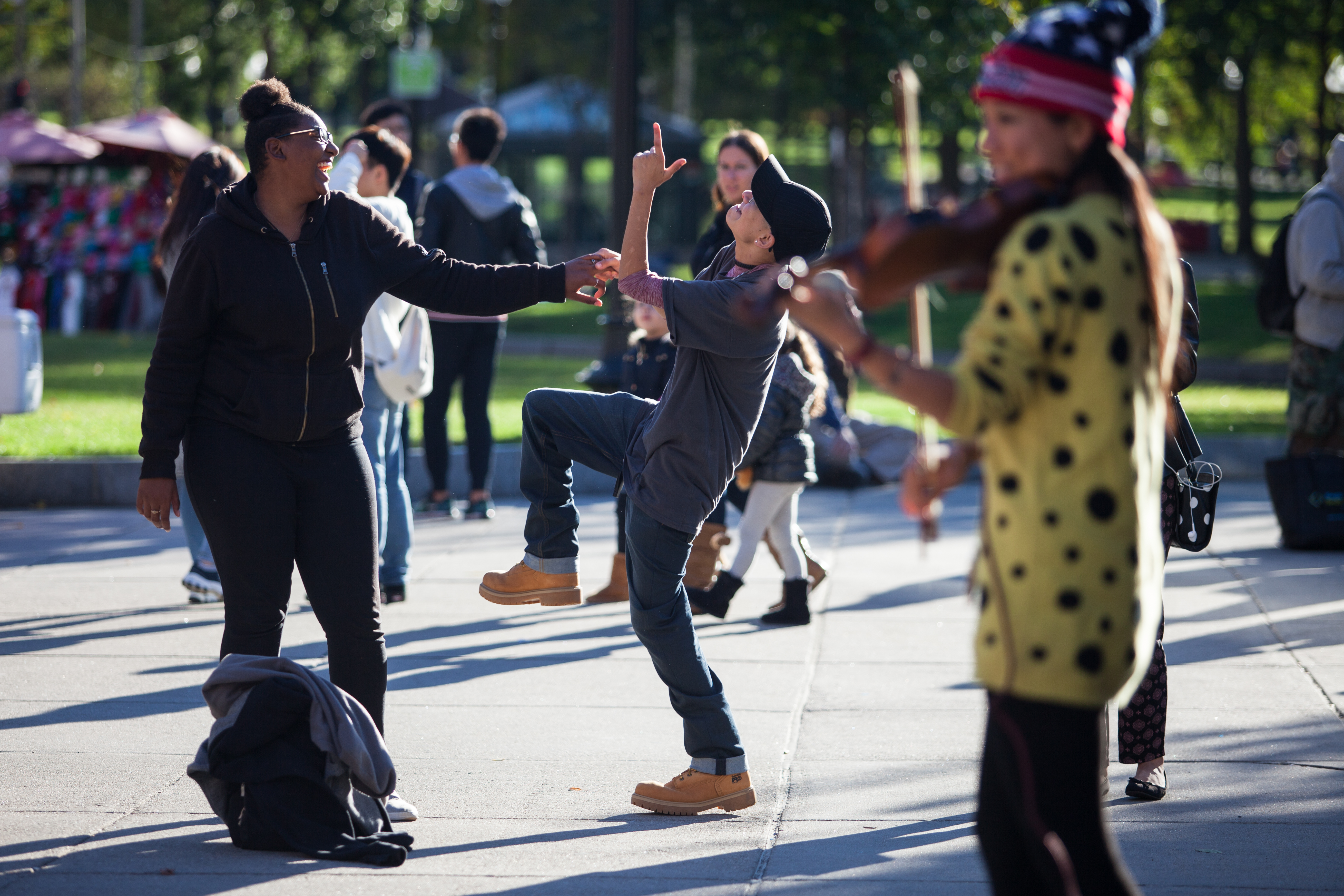 Liniște, right, a 22-year-old gay woman experiencing homelessness, dances with her girlfriend Tay during a violin performance in the Boston Common. Liniște and Tay say they have seen this performer, known as ViolinViiv on social media, in the past and have enjoyed dancing to her performances. "When things get too much, I dance," Liniște says. Photo by Mike DeSocio.